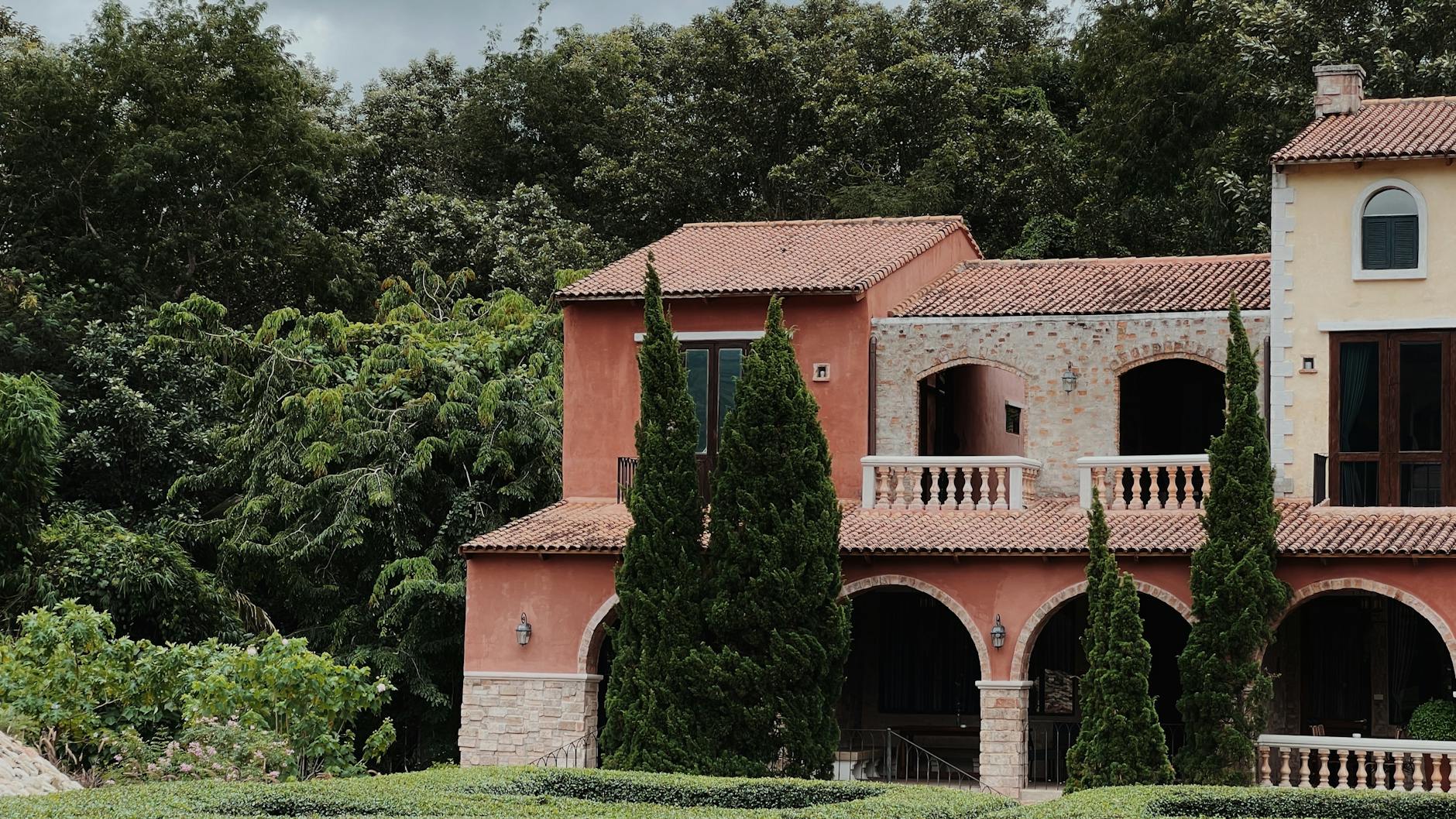 Garten und Hauseingang einer hellen Villa unter Bäumen