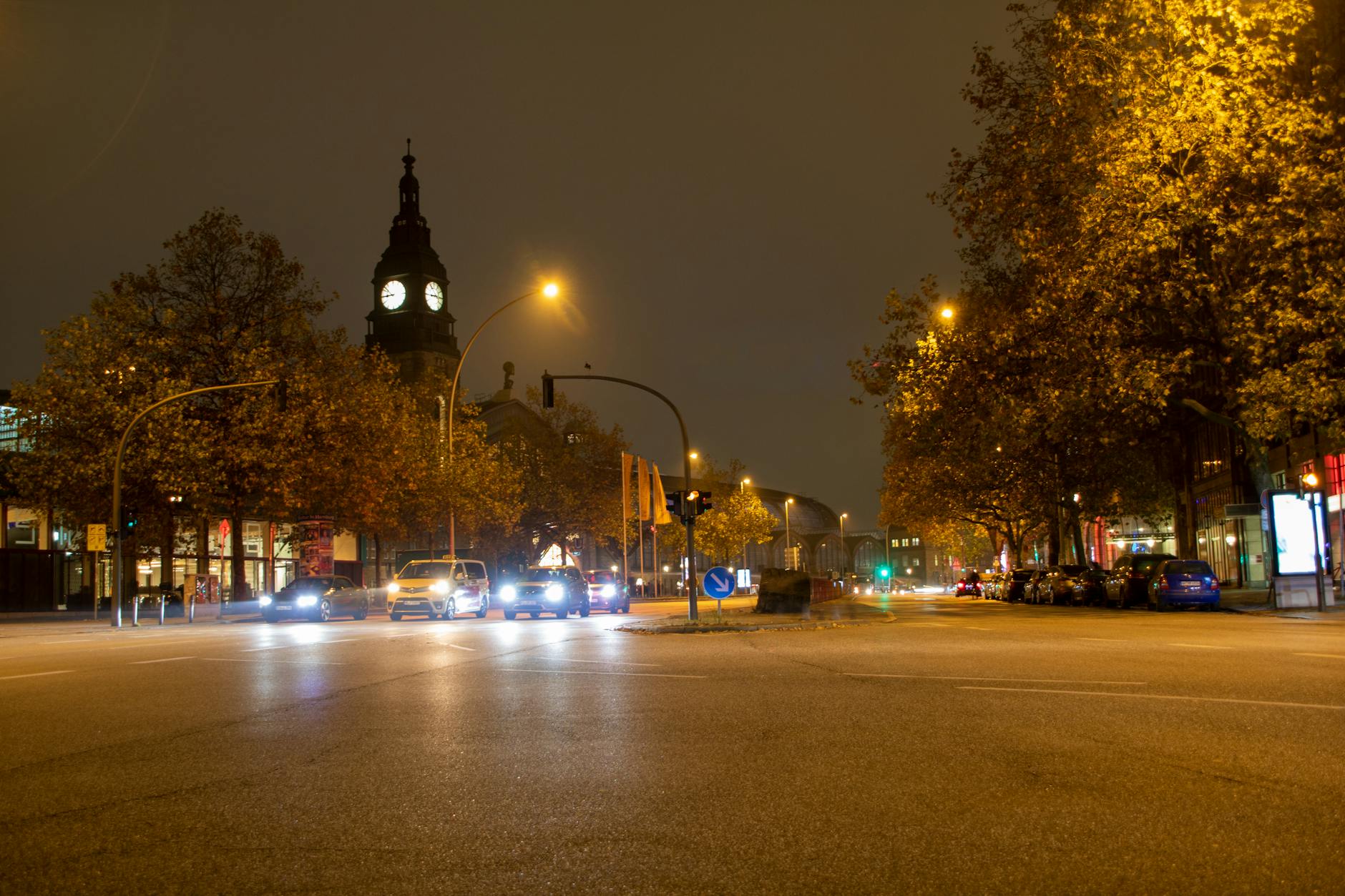 lokaler Innenstadt bei Nacht, ein Kirchturm und herbstliches Laub.