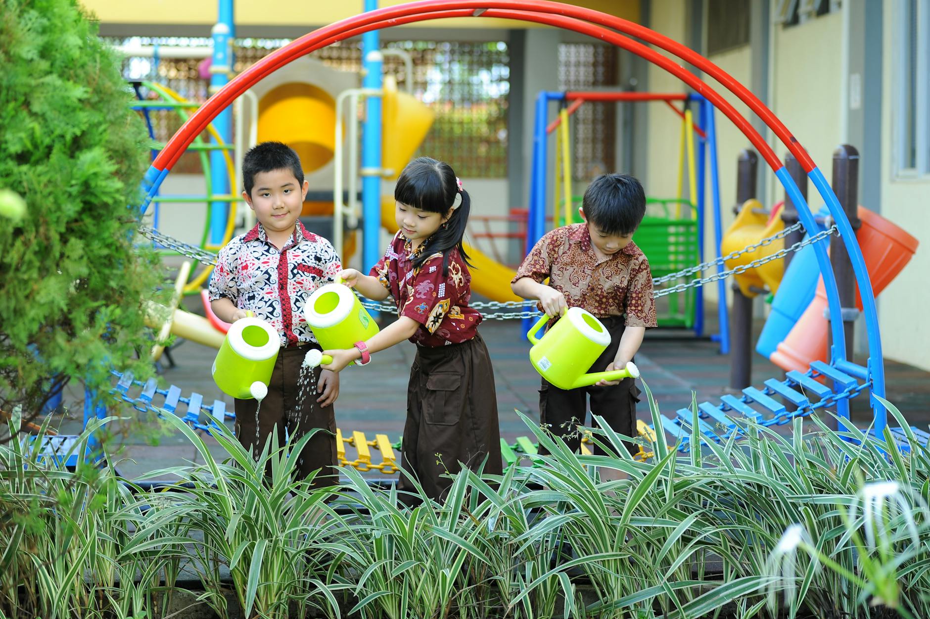 Kinder mit Gießkannen im Schulgarten